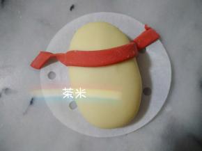 一条红面片，沾水贴在白面团的三分之一处。