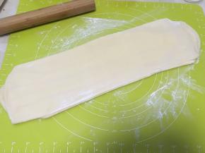 撒点干粉，再用擀面杖将面片擀长，这次的长度是之前的三分之二