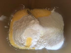 面包桶内加入高筋面粉，低筋面粉，奶粉，全蛋液，细砂糖跟酵母，加水启动揉面程序揉成面团