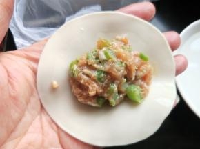 手上蘸清水沿饺子皮抹一圈，放适量的肉馅。