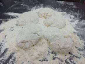 案板上多放一些面粉，把发好的面放在案板上，分成几份