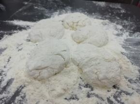 案板上多放一些面粉，把发好的面放在案板上，分成几份