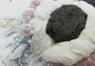 取一份面团用手按扁，然后把芝麻馅放入中间