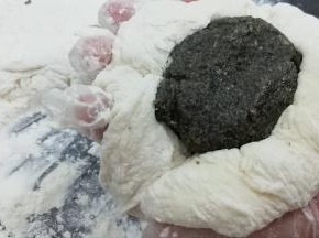 取一份面团用手按扁，然后把芝麻馅放入中间
