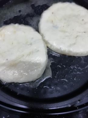 锅里放入适量的油烧热后，把饼坯放入锅中，用手按扁