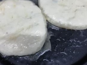 锅里放入适量的油烧热后，把饼坯放入锅中，用手按扁