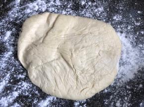 按台上撒一些干粉，拿出冷冻好的面块，擀成红豆沙两倍长，同样宽的长条