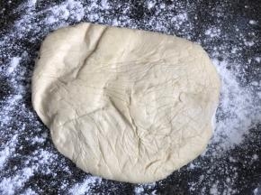 按台上撒一些干粉，拿出冷冻好的面块，擀成红豆沙两倍长，同样宽的长条