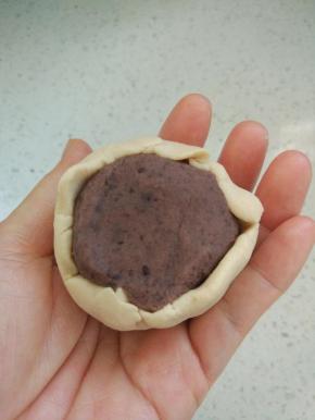 用皮把馅包进去，虎口收圆，和做广式月饼的手法一样。滚上熟糯米粉，用模具压在烤盘上。