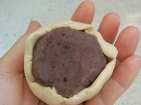用皮把馅包进去，虎口收圆，和做广式月饼的手法一样。滚上熟糯米粉，用模具压在烤盘上。