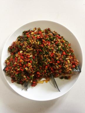 把炒好的剁椒均匀的铺在鱼头上。