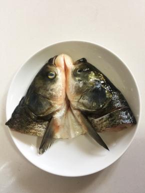 鱼头处理干净，对半剖开，有鱼肉的地方斜切几刀，加入一勺盐和适量的料酒涂抹均匀腌制15分钟。