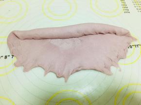 将擀好的牛舌型翻面！翻面！翻面！旋转成横向。按薄底部。从上往下卷，边卷边按。捏紧收口，将面团搓成长条。