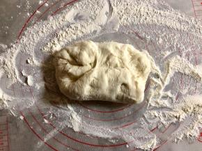 台面上撒上干粉，把面团取出，进行按压排气。