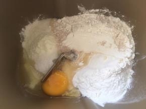 面包桶内加入高筋面粉，低筋面粉，奶粉，炼乳，鸡蛋，细砂糖根酵母，加水启动揉面程序活成面团