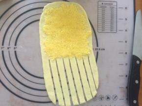 拿出一个面团，擀成长方形，上面铺上椰蓉馅，下面用刀划成一条一条的形状