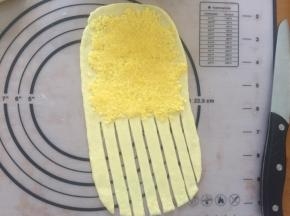 拿出一个面团，擀成长方形，上面铺上椰蓉馅，下面用刀划成一条一条的形状