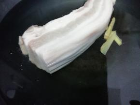 锅中加入适量的水倒入料酒和姜片，再把洗干净的五花肉放入锅中焯水