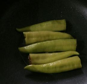 用筷子把肉塞入尖椒里，尽量塞紧实。热锅凉油下尖椒。
