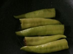 用筷子把肉塞入尖椒里，尽量塞紧实。热锅凉油下尖椒。