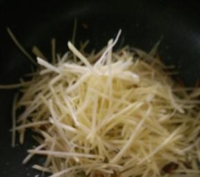 然后倒入沥水后的土豆丝，快速翻炒。