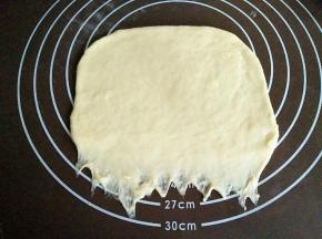 把面团擀成圆饼状，底部用手按压变薄，如图