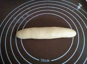 一边从上往下用力按压，一边转动面团，搓成约18厘米的棒状