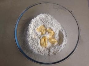 将面粉、泡打粉、盐和糖倒入和面盆里混合，加入切成小块软化的黄油