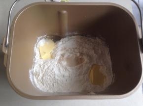 将水、糖和盐倒入东菱面包桶里，加入切成小块的黄油和面粉，在面粉顶端加入酵母