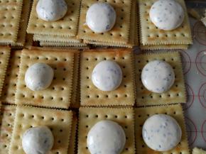 待牛轧糖稍微冷却后就不会粘了，戴上手套，取适量牛轧糖搓圆，放到饼干上（也可以用自己觉得合适的工具），盖上另一片饼干，轻轻压一下