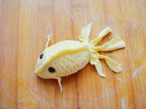 抹少许水沾上黑豆做眼睛，利用吸管的半圆形状在鱼身的两侧刻出鱼鳞。