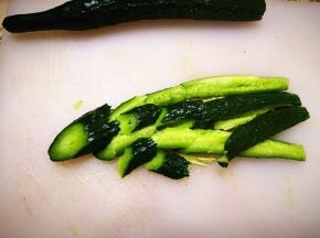2．	黄瓜清洗干净，去根，竖着切成两半，再用刀拍几下，然后斜着切成大小适中的黄瓜块，这样黄瓜拌的时候会比较入味，