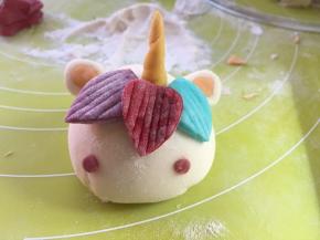 沾点水，将耳朵黏在角的两侧，喜欢萌一点的，可以取两小块红色面团，搓圆装点在棕毛下面的两侧作为红脸蛋