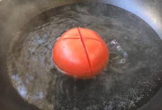 在番茄上边切个十字，放在开水里焯烫，焯烫至表皮裂开。