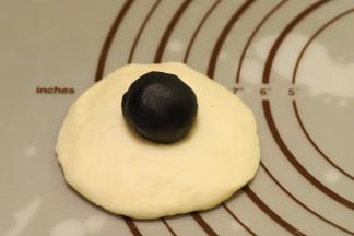 再次将面团排气整圆，擀成圆片，黑芝麻馅平均分成9份（10克一份），放在面团中间