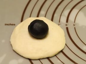 再次将面团排气整圆，擀成圆片，黑芝麻馅平均分成9份（10克一份），放在面团中间