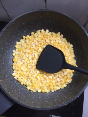 把裹满玉米淀粉的玉米粒倒进锅里，用铲子整理一下，中火煎制定型。