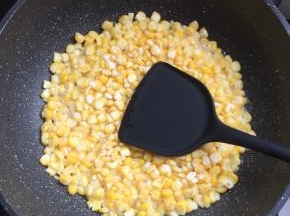 把裹满玉米淀粉的玉米粒倒进锅里，用铲子整理一下，中火煎制定型。