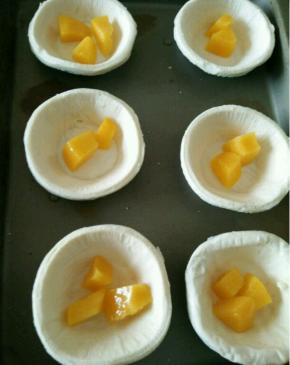 拿出蛋挞皮，放入适量黄桃粒。