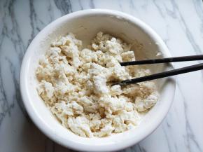 面粉中分次加入开水，边加开水，边用筷子搅拌，搅成絮状，再揉成面团，盖上盖子醒15分钟。