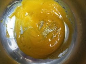 镜面材料中的60克芒果泥加入半片吉利丁片，小火加热至吉利丁片完全溶化。