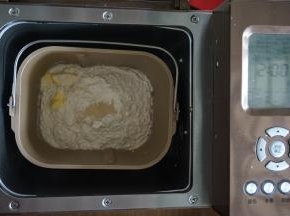 加入面包粉、黄油，在面粉顶端加入酵母，因为黄油量不多，所以可以在一开始就加入，将面包桶放入到东菱1352AE-3C面包机里