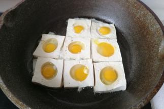 然后再把鹌鹑蛋打碎，填入豆腐的圆孔中，开中小火煎制。