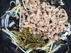 加入猪瘦肉丝和泡椒丝，炒匀