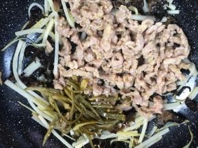 加入猪瘦肉丝和泡椒丝，炒匀