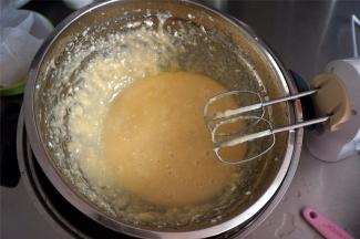 将打发好的蛋白坐入热水浴中，启动打蛋器，边打边倒入糖浆，搅打混合后，将融化了的黄油分两次加入，搅打融合。