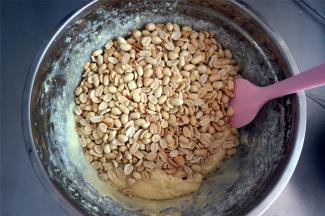 取出烤箱中温热的花生肉，倒入，用橡皮刮刀拌均匀。