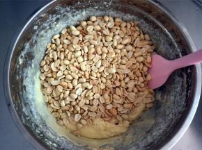 取出烤箱中温热的花生肉，倒入，用橡皮刮刀拌均匀。