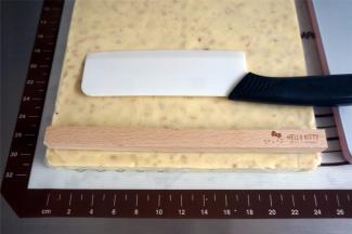 借助四件套中的方形木棍将牛轧糖切成均等宽度的长条。