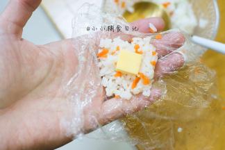 10、	取一小块饭，加入一块芝士，用保鲜膜包起来